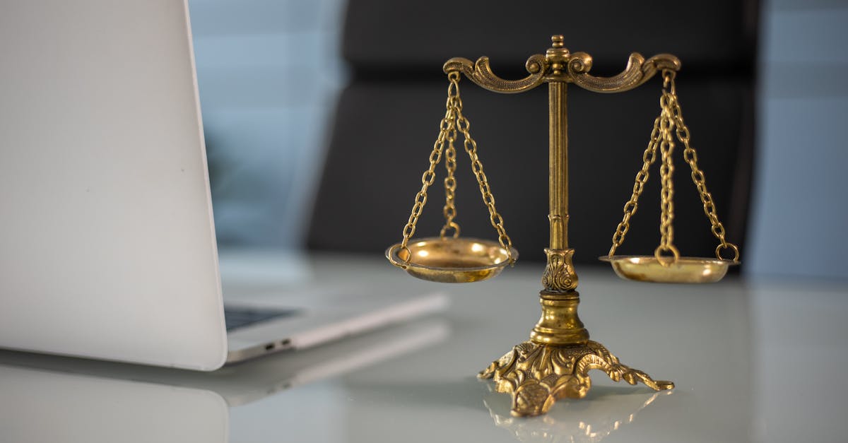 golden justice scales on a desk beside a laptop symbolizing law and balance